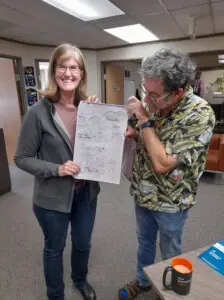 Dr Jenny Pope holding a piece of paper with Dave Nordquist